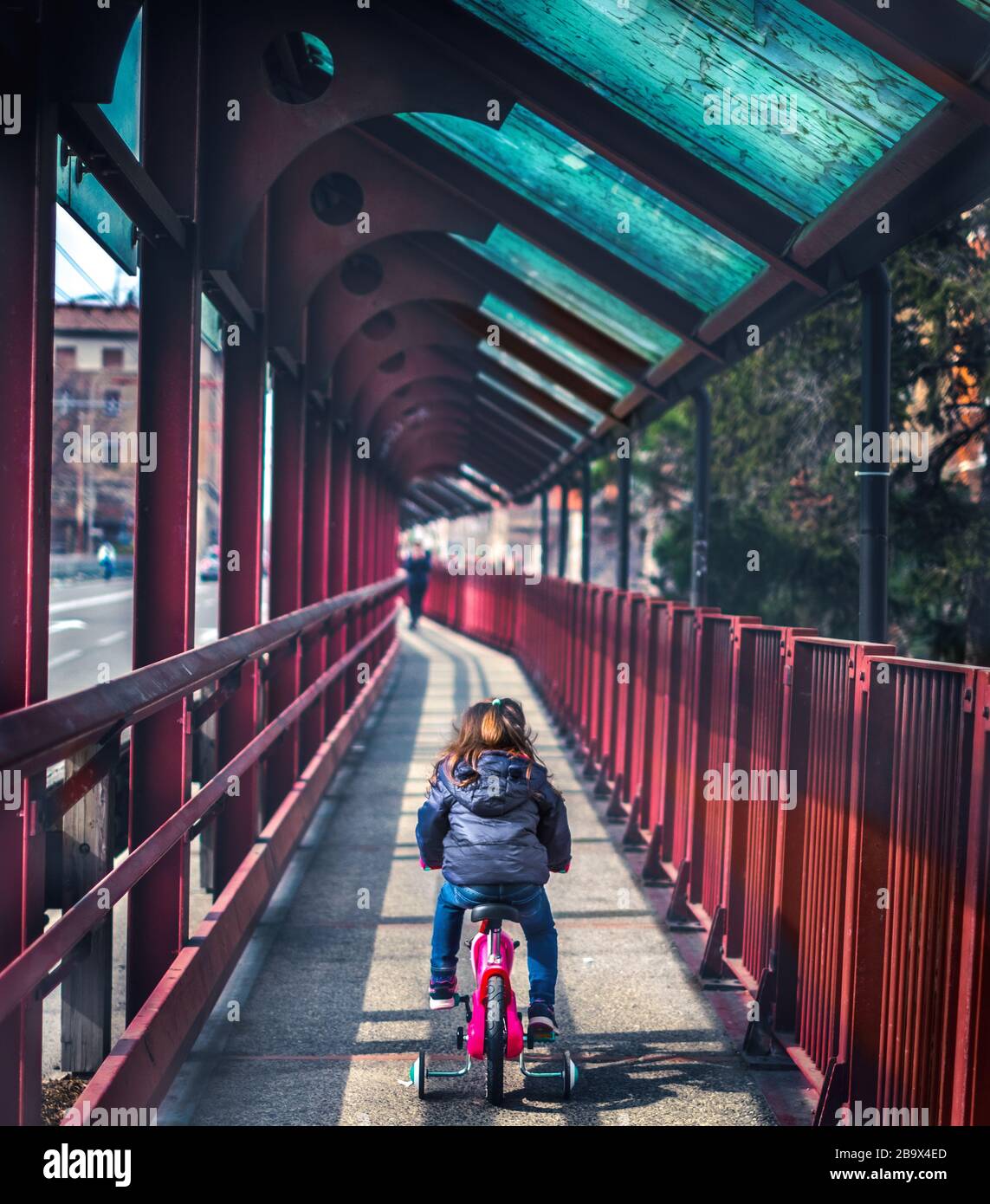 baby cycling seen from back background of red bridge deserted with no people Stock Photo