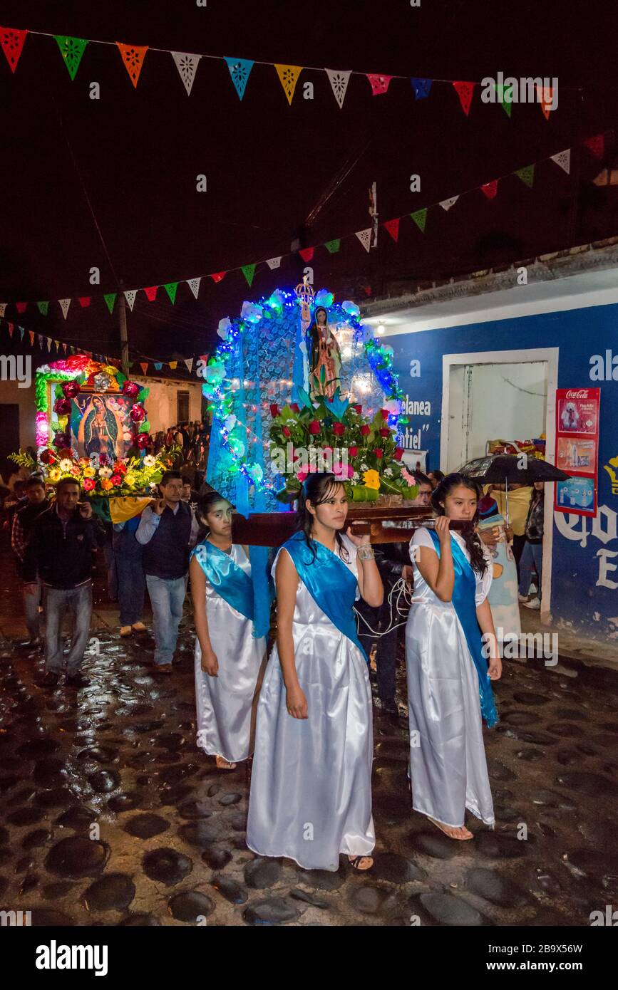 Girls carrying Virgin Mary image at procession, Festival of Our Lady of Guadalupe in December, rainy night in Coscomatepec, Veracruz state, Mexico Stock Photo