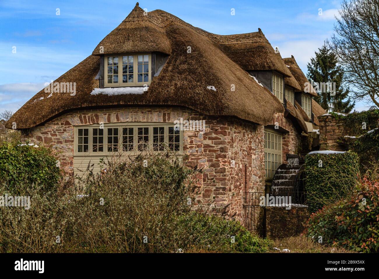 Cockington Mill Cottage with water wheel, in Cockington country park, Torquay, Devon, UK. March 2018. Stock Photo