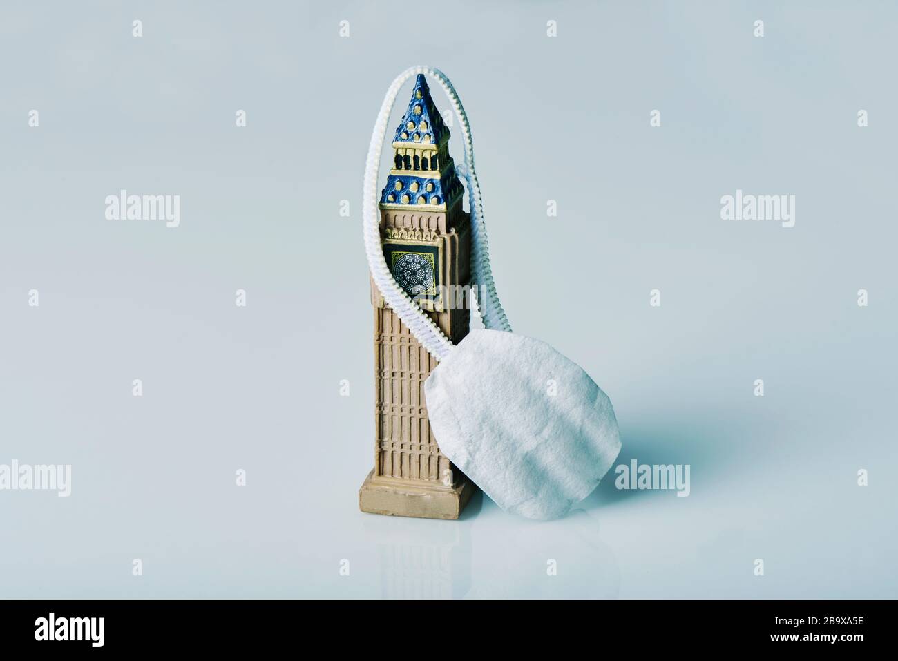 a miniature of the big ben, icon of the United Kingdom, and a face mask on an off-white background Stock Photo