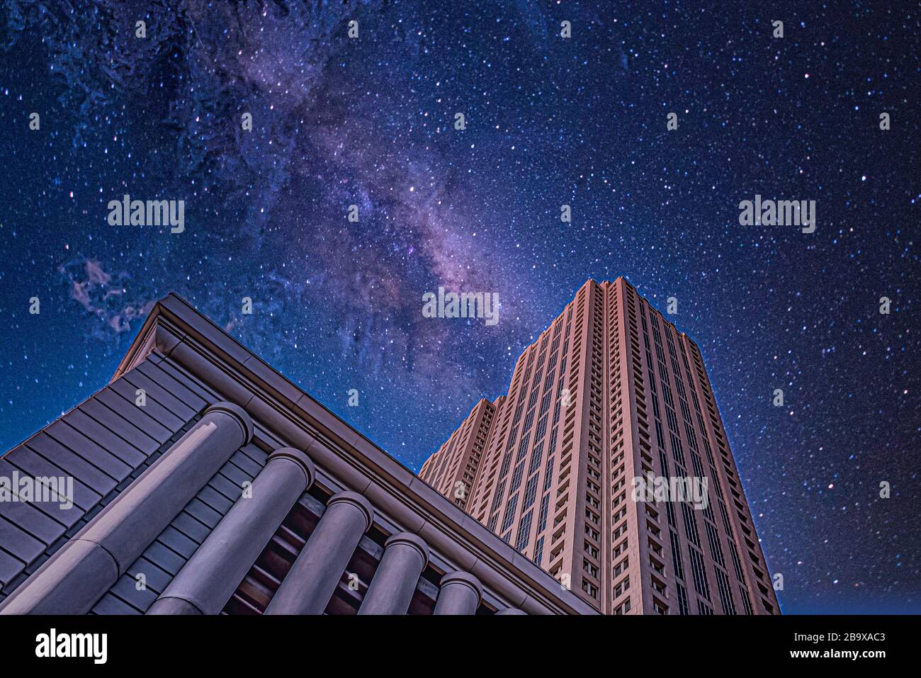 Low angle shot of tall buildings under a starry night sky Stock Photo