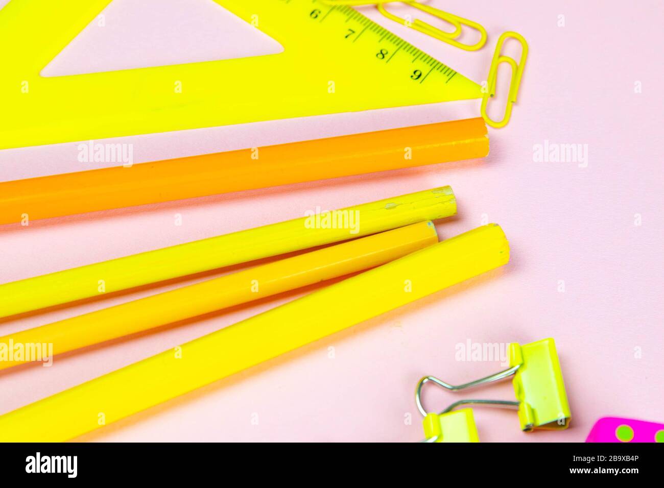 Multi-colored red yellow pinc pencils rulers, pens, pencils and scissors and stationery stand on a pink background Stock Photo