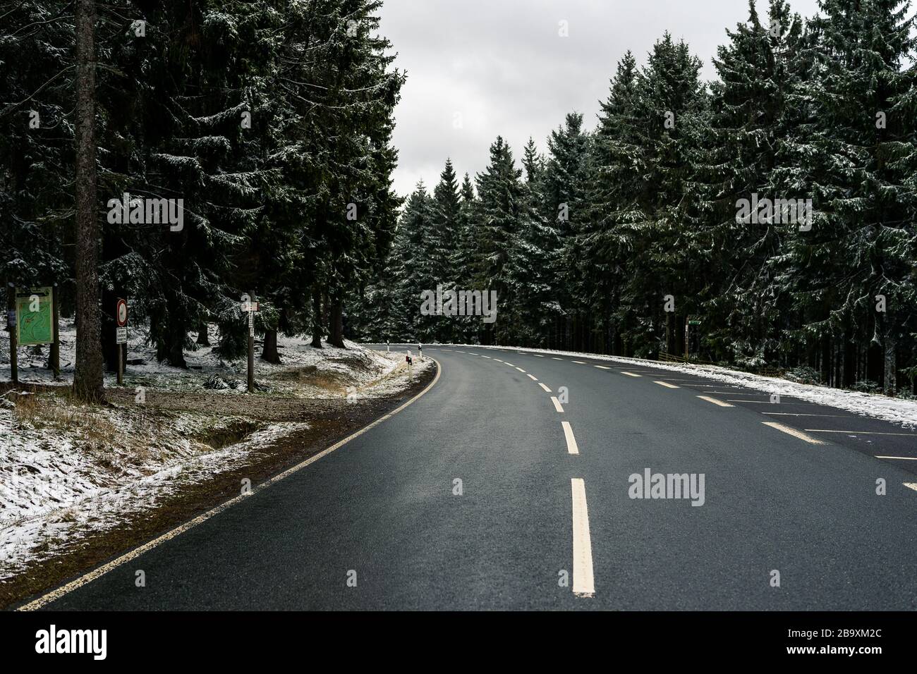 curved wet asphalt road in snowy pine forest Stock Photo - Alamy