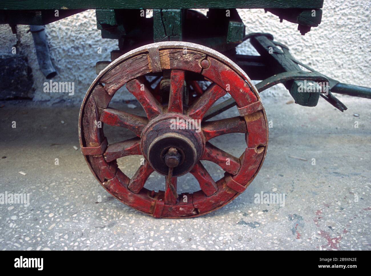A handmade, red painted, wooden cart wheel with an iron tyre on a