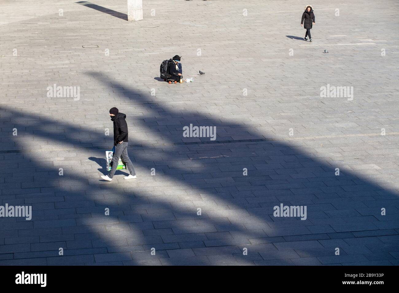 Coronavirus / Covid 19 outbreak, March 24th. 2020. Only few people on the square in front of Cologne central station, shadow of the cathedral, Germany Stock Photo