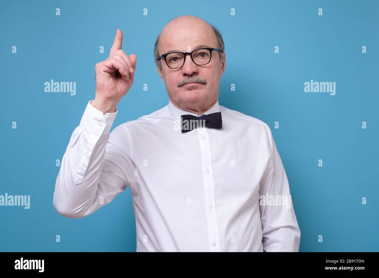 Strict senior man showing index fingers up, giving advice Stock Photo