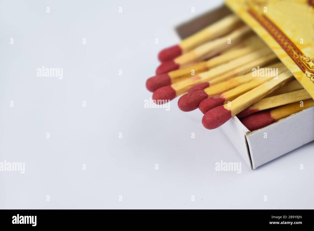 Close up picture of some flammable red fire matches gathered in a small match box before white