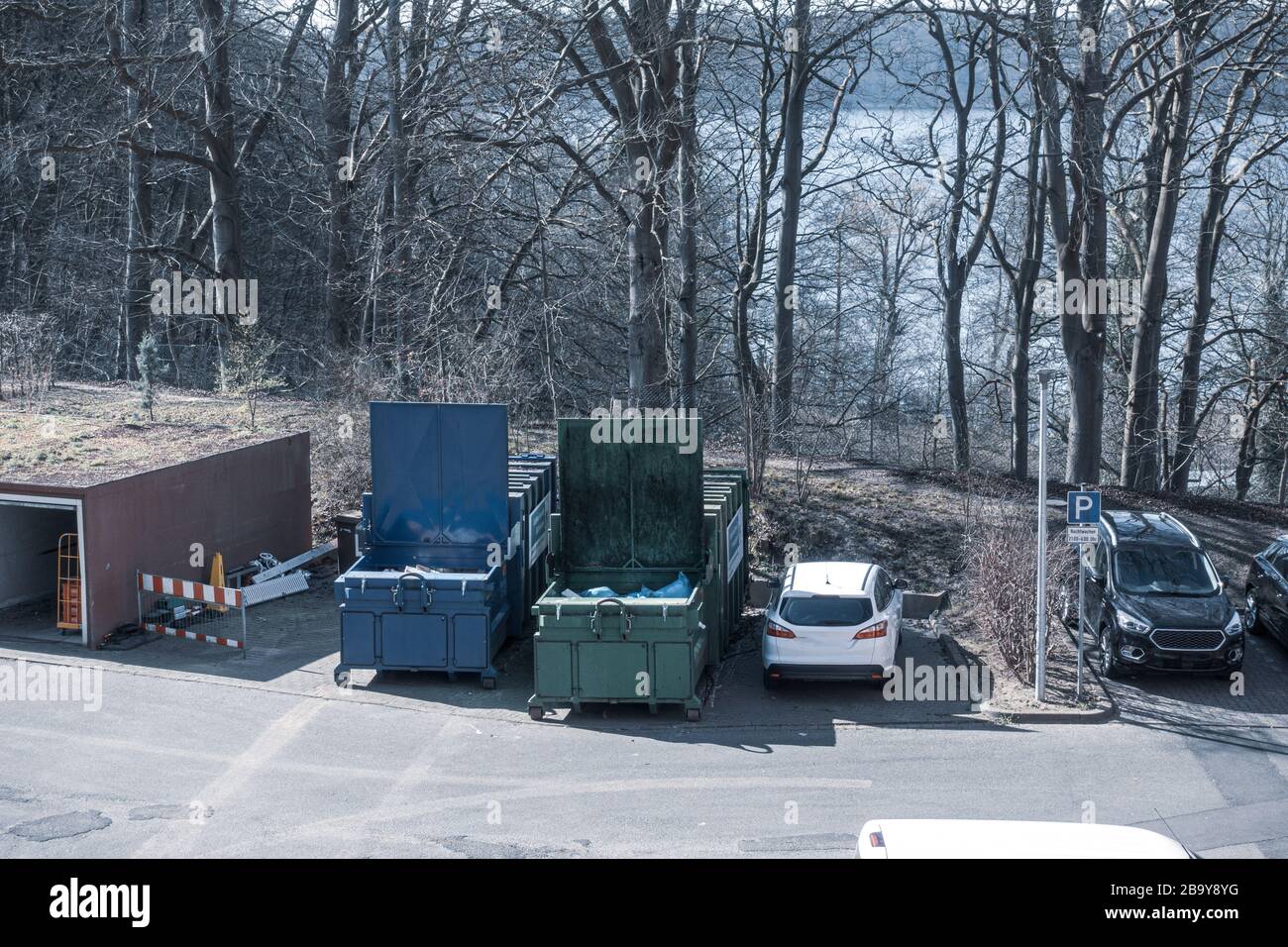 in the yard of a hospital, two waste compactors stand side by side ...