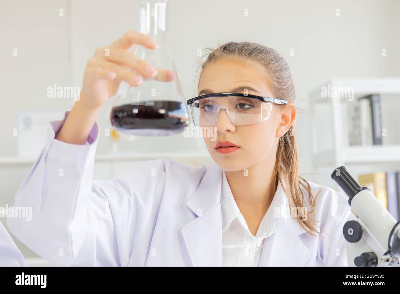 A beautiful female scientist is operating in a science lab with various equipment in the lab