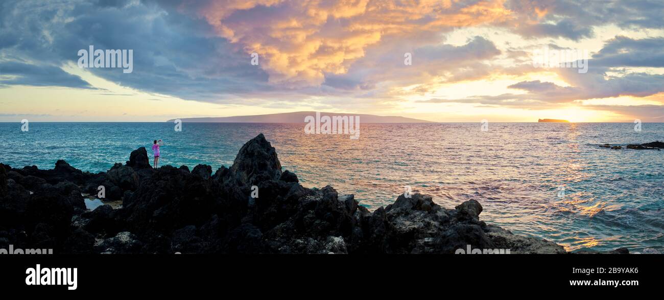 Woman taking a photo of the sea at sunset. Stock Photo
