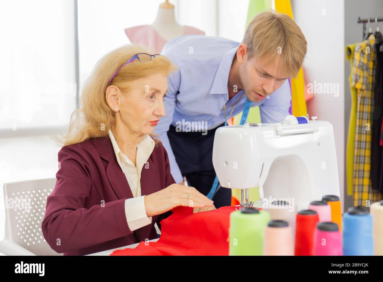 Professional team work designers, young men and elderly women in the office with a variety of fabric tones and equipment for various designs. Stock Photo
