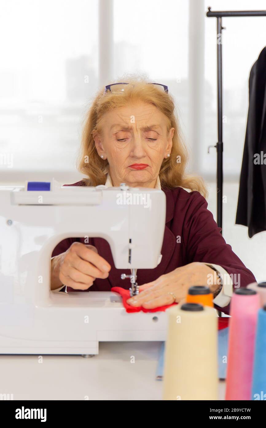 Professional female designers are sewing with small sewing machines on