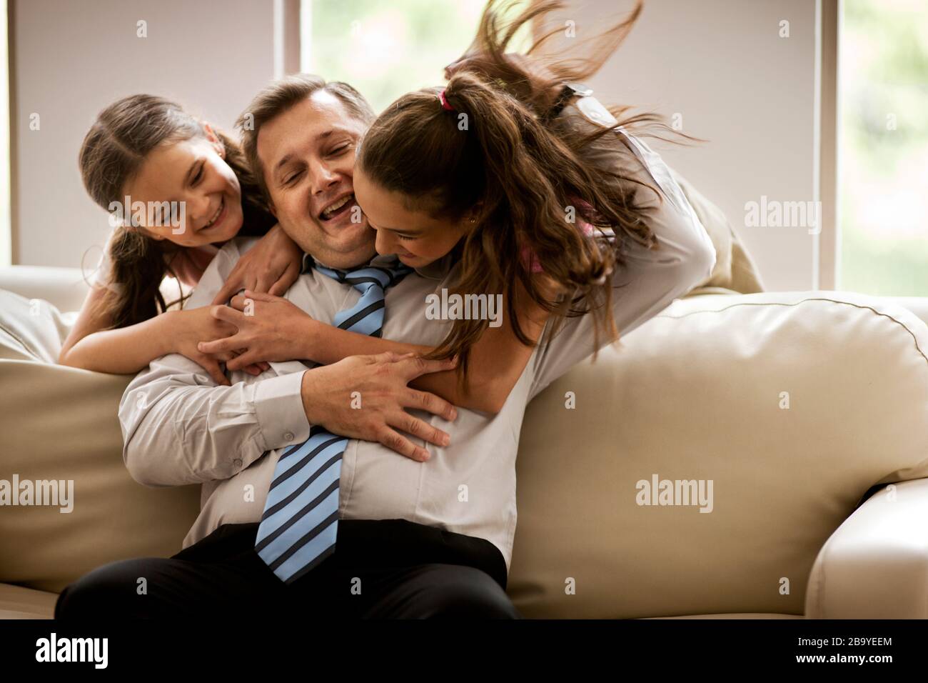 Man getting a hug from his two daughters Stock Photo - Alamy