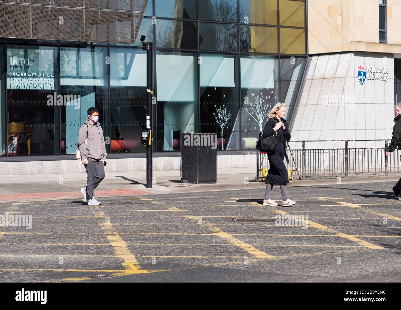 Newcastle upon Tyne, UK, 19th March 2020,. An asian crosses from Newcastle University wearing a mask as protection against corvid-19, the coronavirus Stock Photo