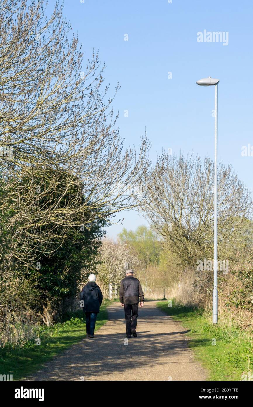 25 March 2020. King's Lynn, Norfolk, UK.  An elderly couple take their daily exercise during the Covid-19 Coronavirus pandemic while maintaining the required social distancing from other people.  Credit: UrbanImages-News/Alamy Stock Photo