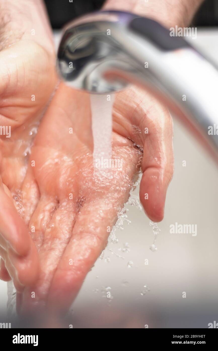 Hands under running sink faucet washing with soap and warm water, vertical. Stock Photo