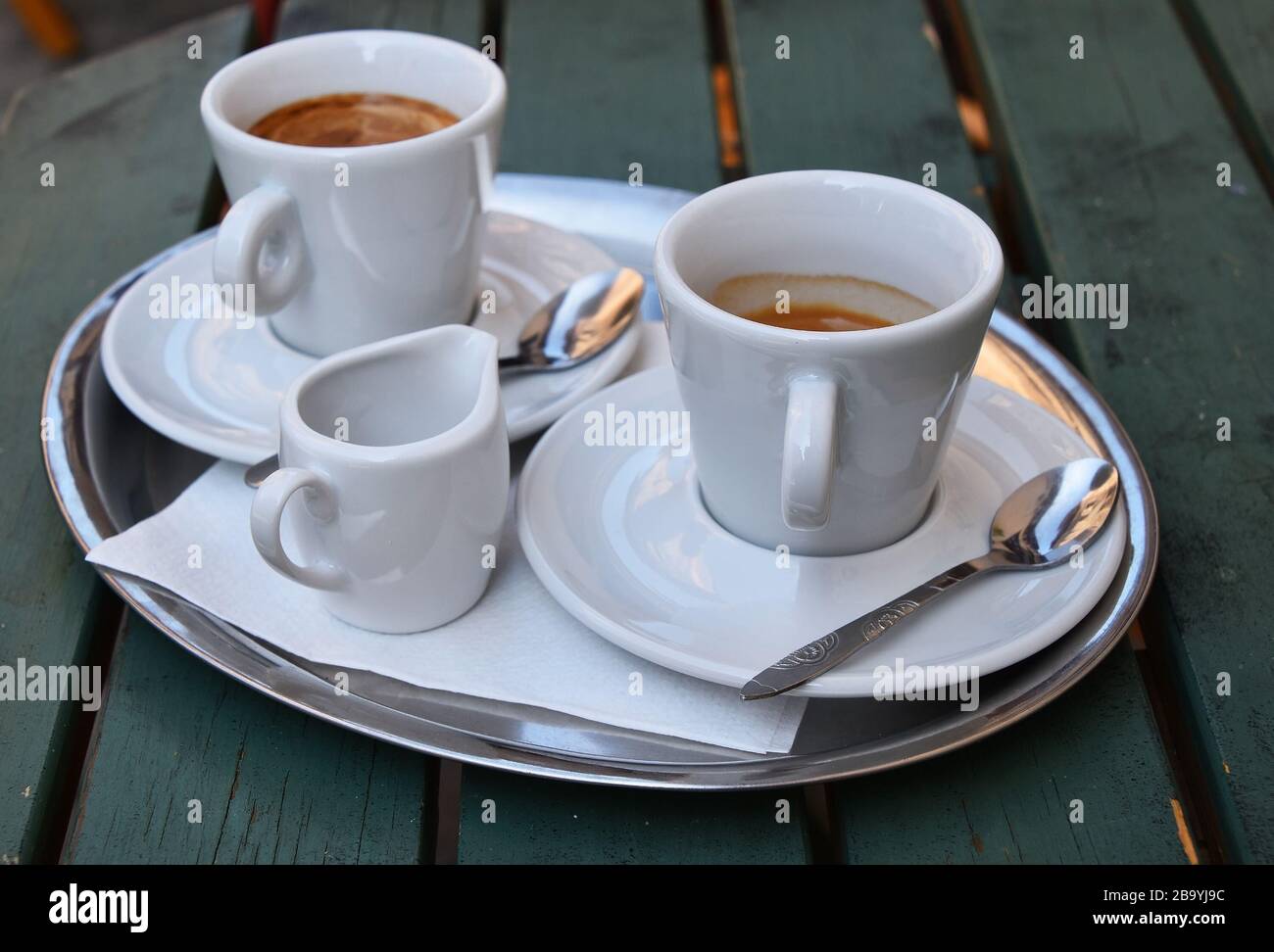 Close up one silver metal tray with white cups of espresso coffee on saucers with spoons and
