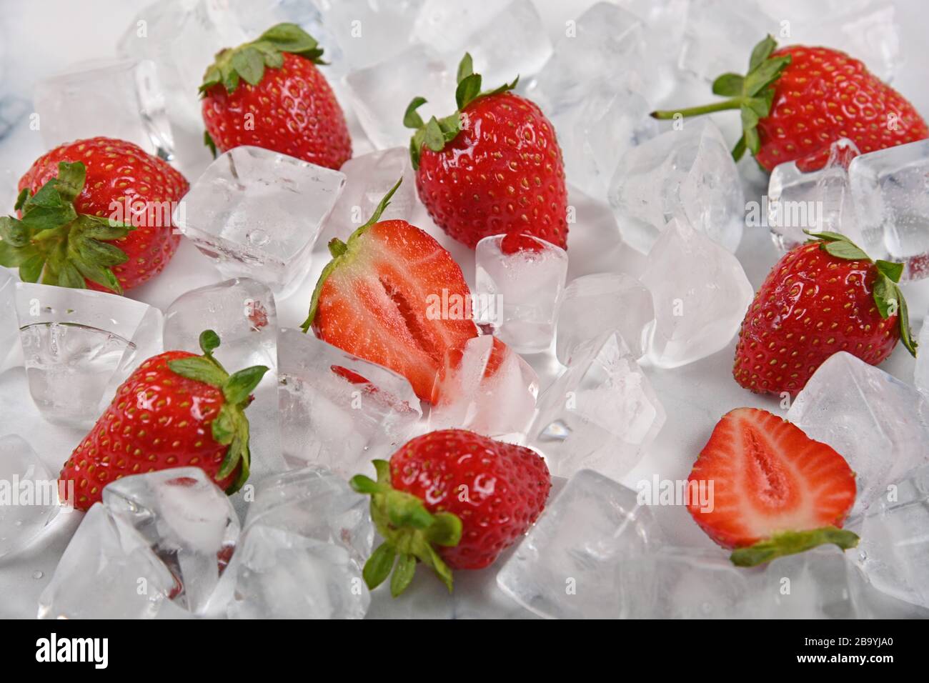 Close up fresh red ripe strawberries and ice cubes on table, high angle view Stock Photo