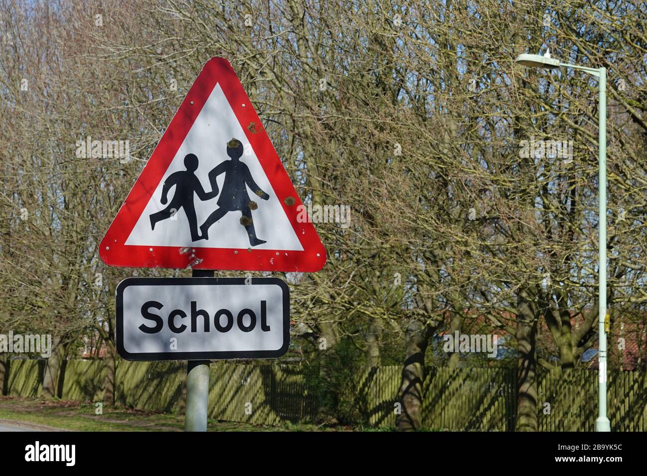 Martlesham Heath, Suffolk - 25 March 2020: Caution children crossing. Red warning triangle road sign near a school. Schools out for coronavirus. Stock Photo