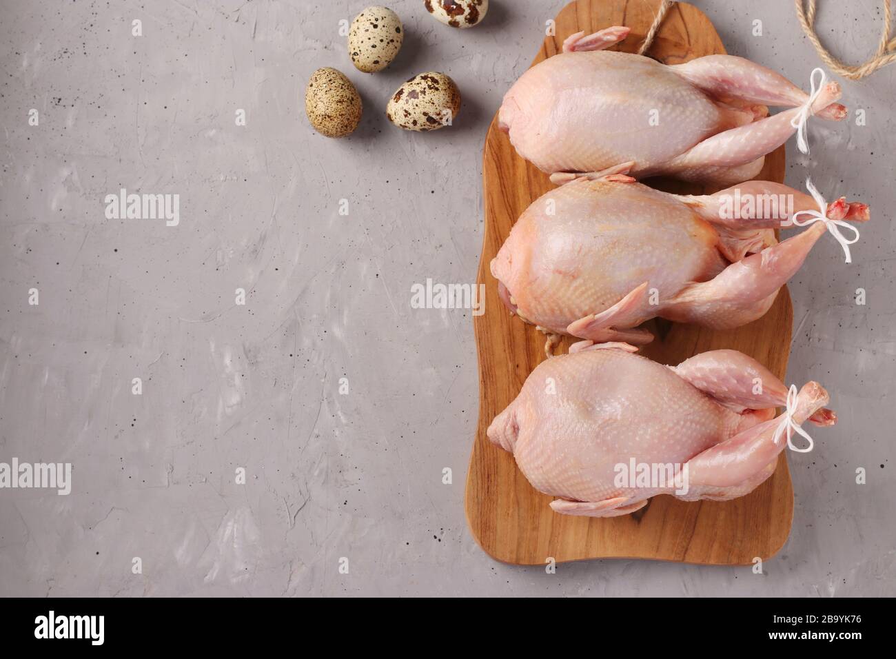 Fresh raw organic quails on wooden board and quail eggs on a gray background, Copy space Stock Photo