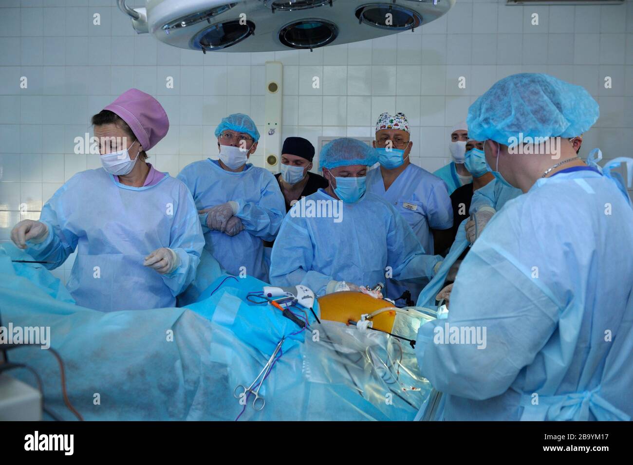 Surgeons in face masks standing around patient plate and performing an operation, artificial lungs ventilation machine working. January 12, 2019. Kiev Stock Photo