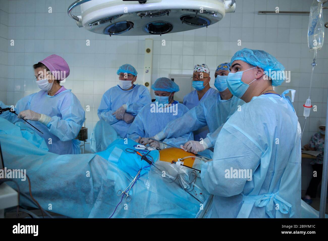 Surgeons in face masks standing around patient plate and performing an operation, artificial lungs ventilation machine working. January 12, 2019. Kiev Stock Photo