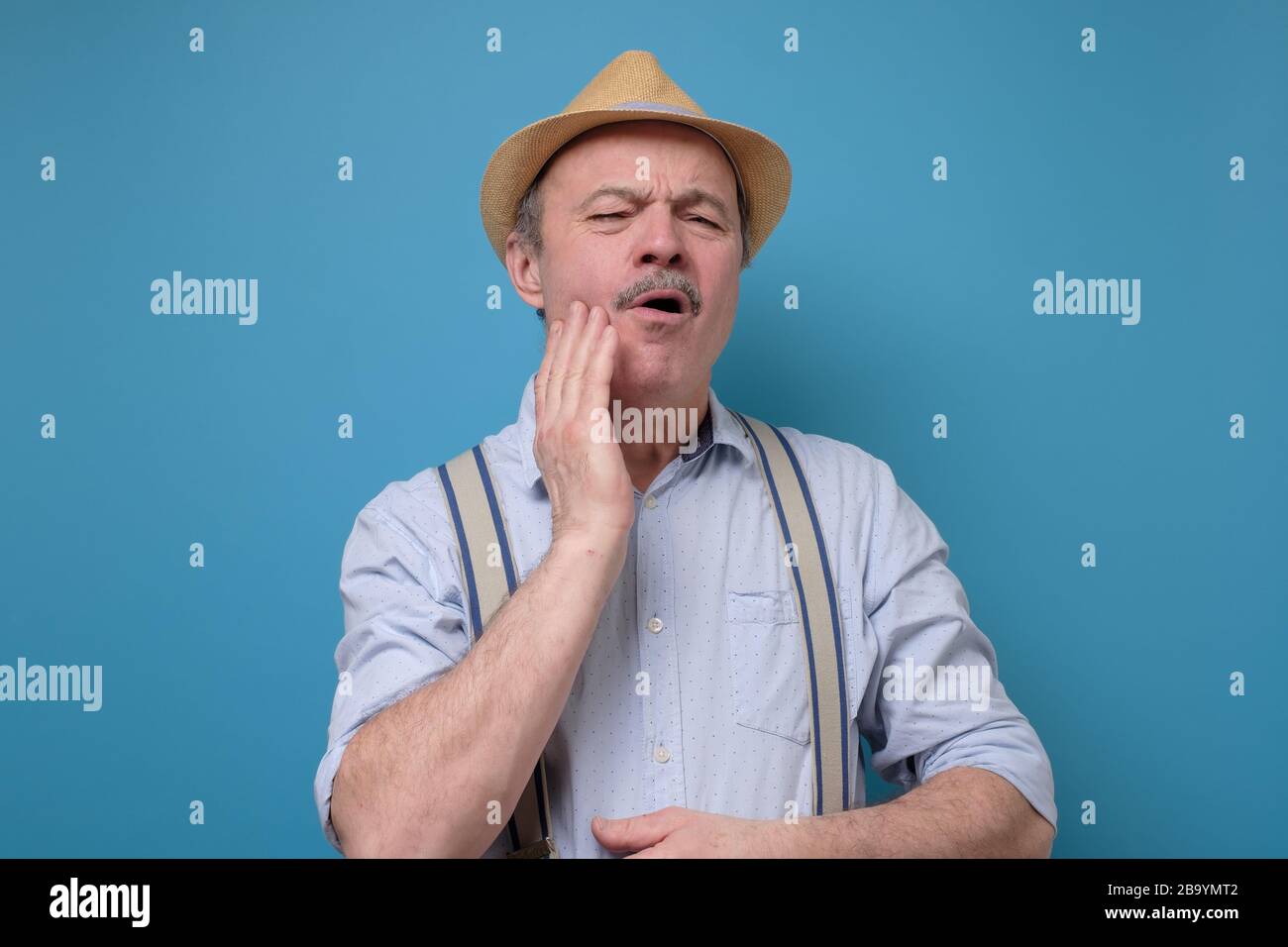 man in summer hat frowning having toothache touching his cheek Stock Photo