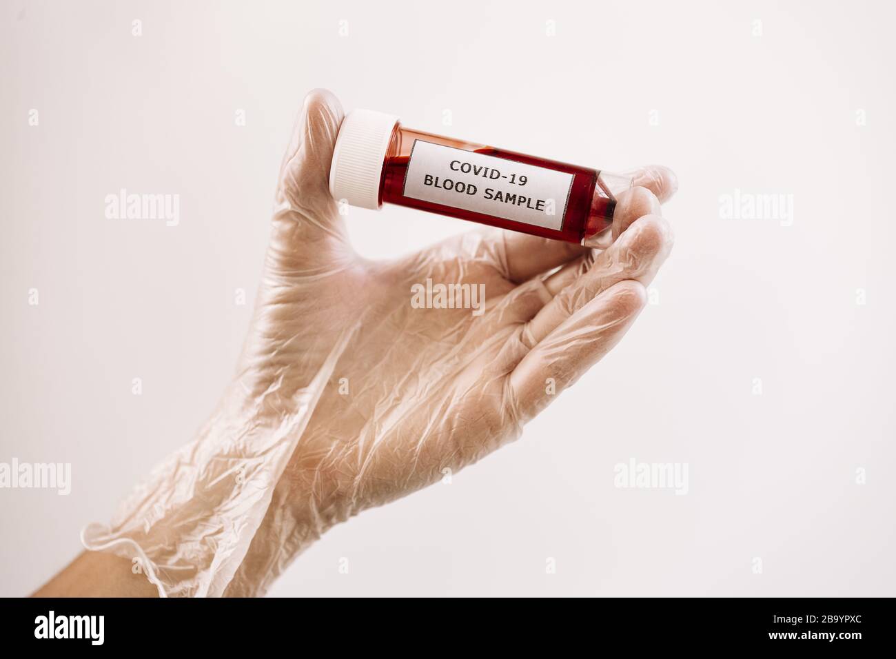 gloved hand taking a vial of blood sample infected with covid-19, medicine concept and protection against viruses and bacteria Stock Photo