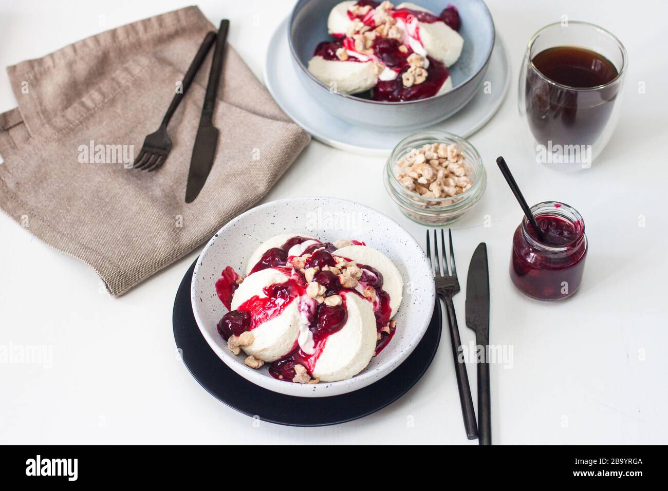 Cottage cheese pancakes with cherry sauce, sour cream and caramelized nuts. Stock Photo
