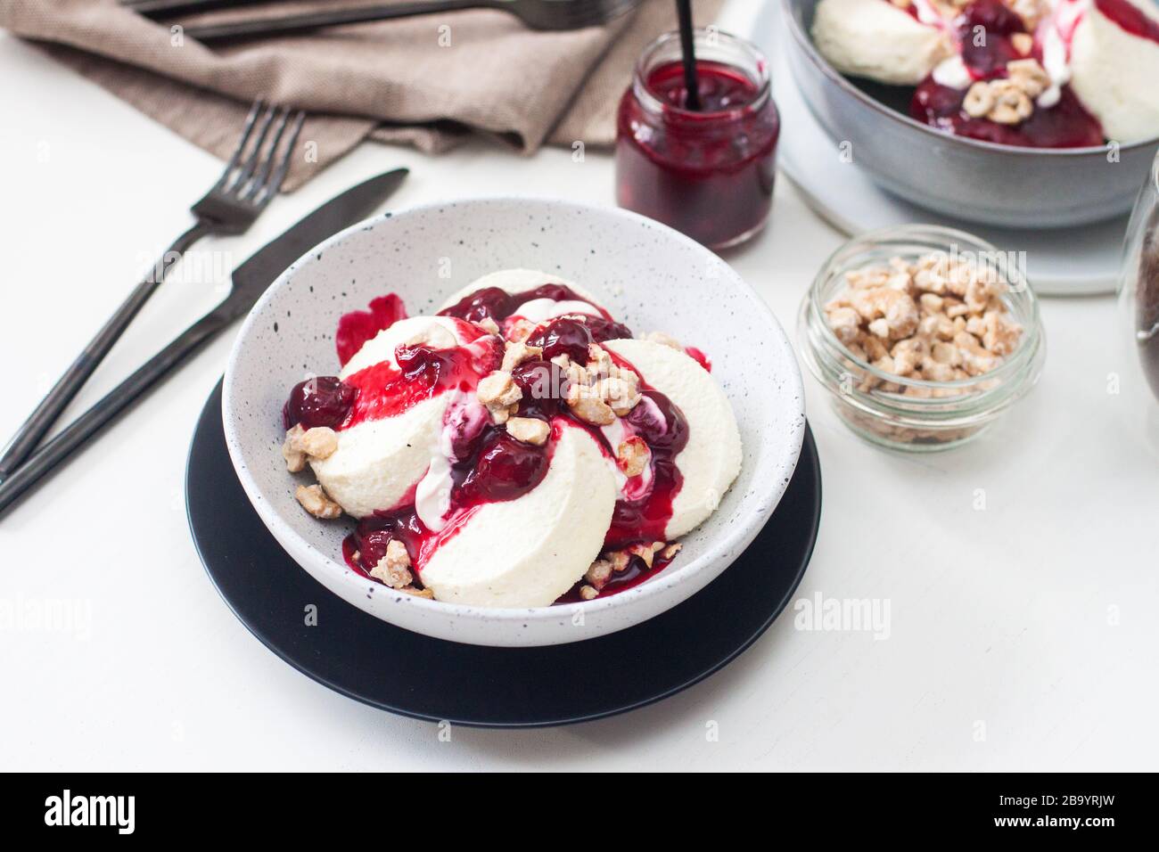 Cottage cheese pancakes with cherry sauce, sour cream and caramelized nuts. Stock Photo
