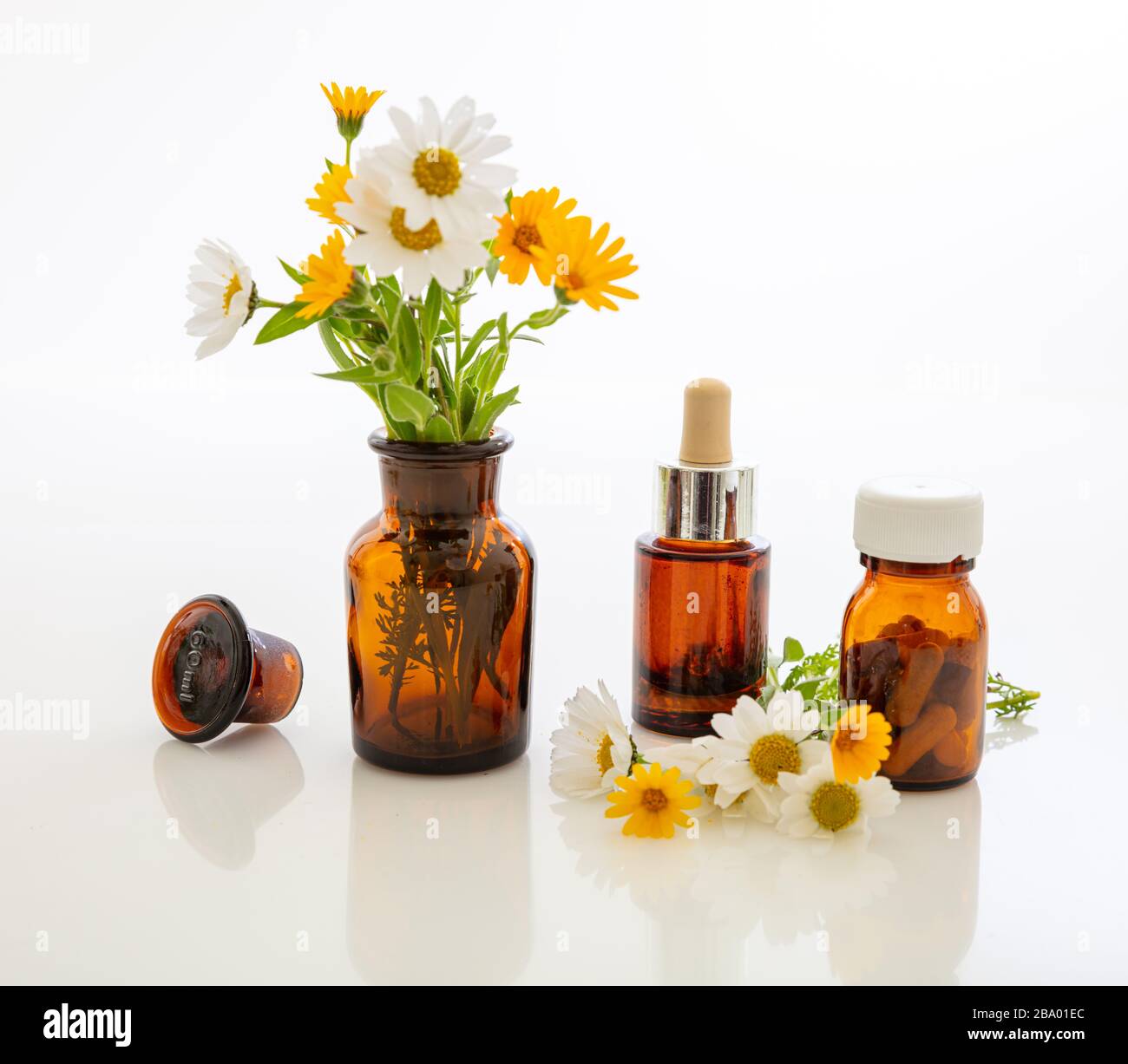 Alternative herbal medicine. Glass medical bottles and fresh wild flowers isolated against white background. Essential oil, cosmetics, medicine contai Stock Photo