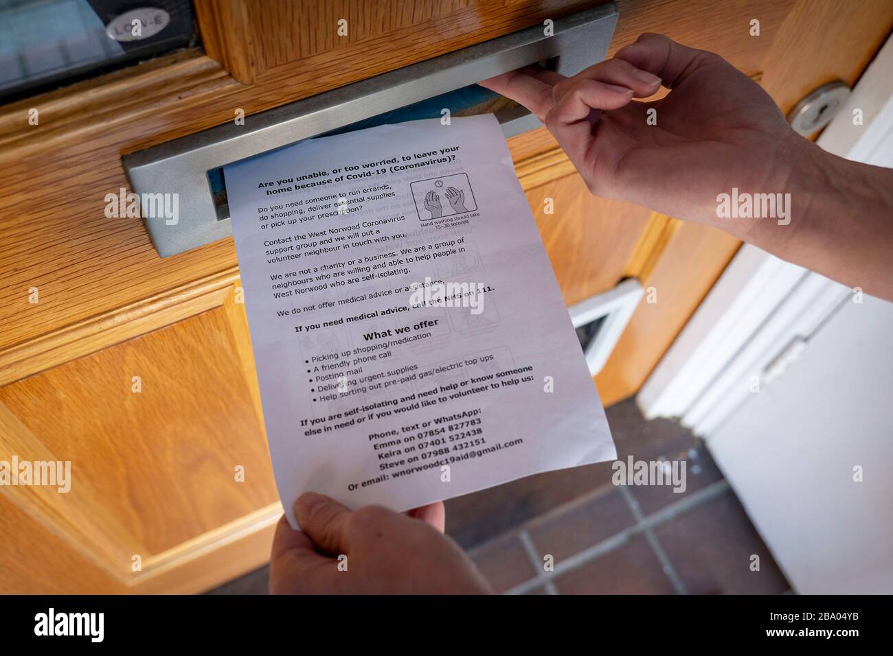 West Norwood, England. 25th March 2020. An A5 flyer providing coronavirus advice being posted through a letterbox. Stock Photo
