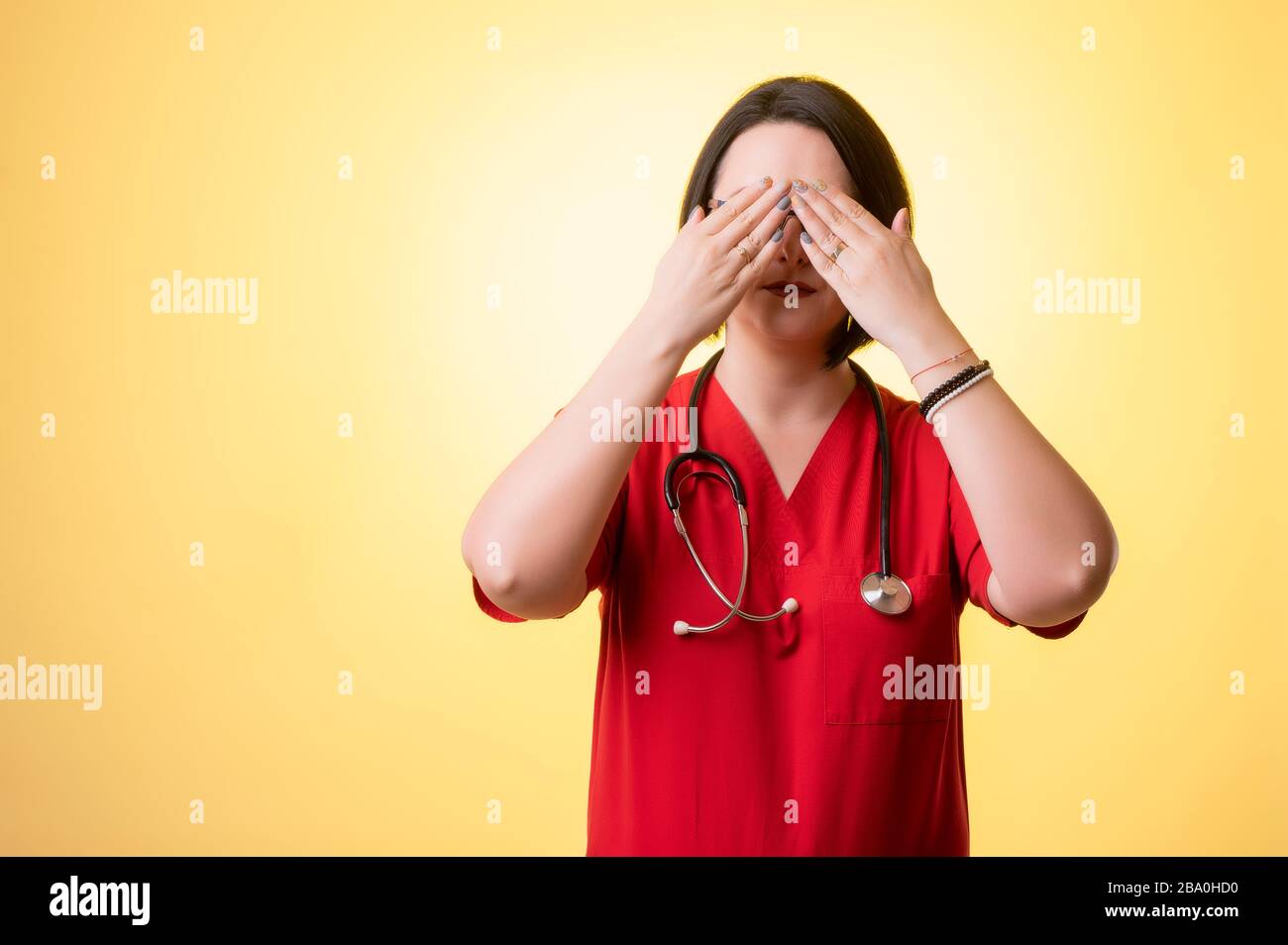 Portrait of beautiful woman doctor with stethoscope wearing red scrubs