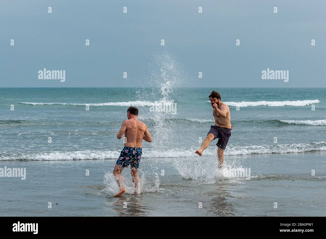 Inchydoney Beach, West Cork, Ireland. 25th Mar, 2020. Two friends have fun in the sea whilst observing social distancing guidelines today. Credit: Andy Gibson/Alamy Live News Stock Photo