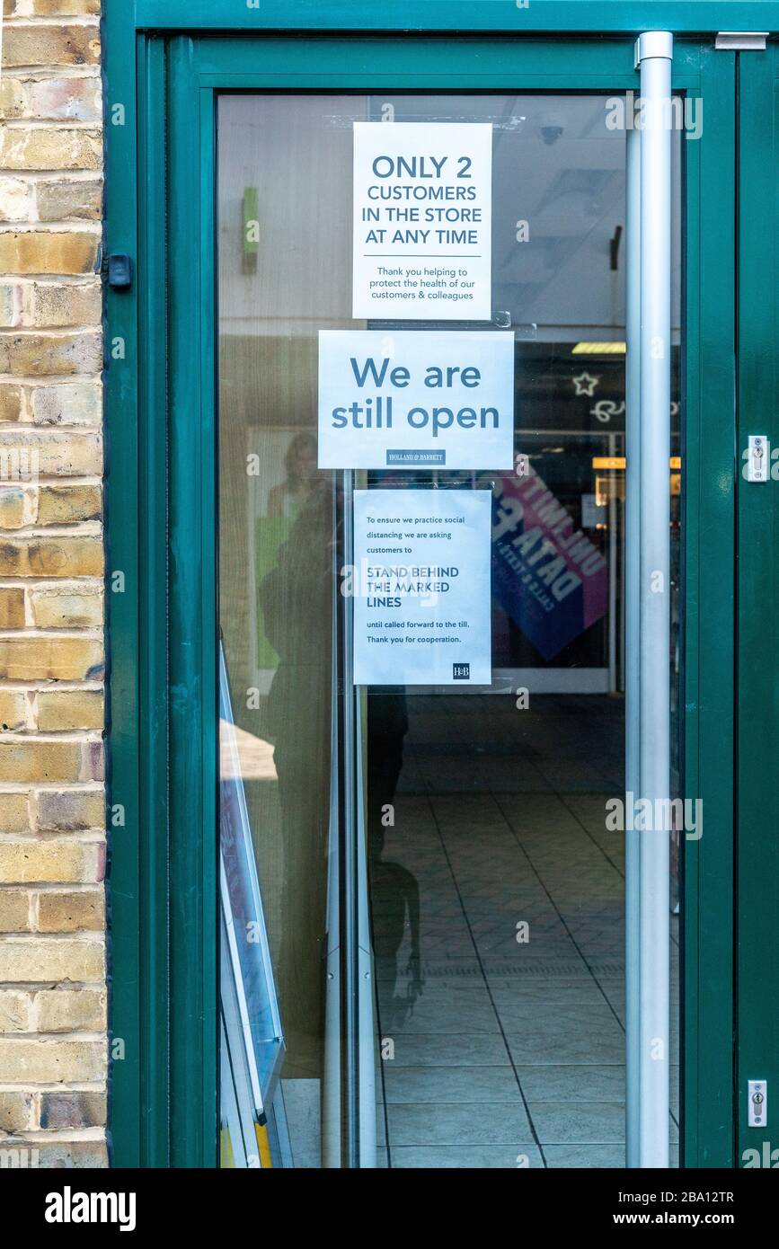 Door signs indicate social distancing measures adopted by UK shops during the UK lockdown  to combat the spread of coronavirus Stock Photo