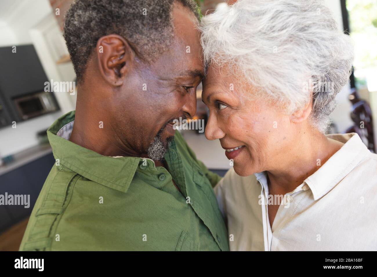 Senior African American couple cuddling in kitchen Stock Photo - Alamy