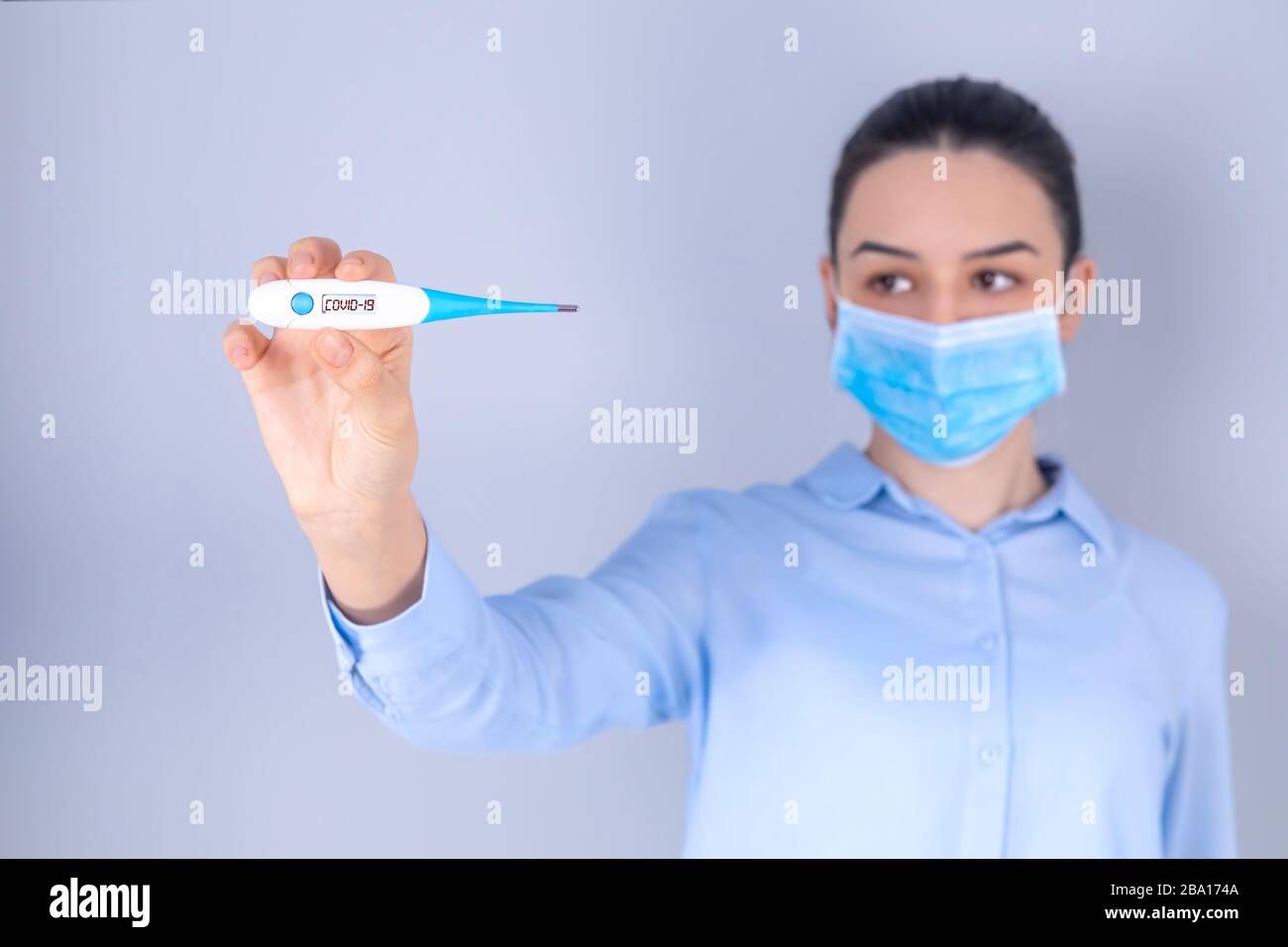 COVID-19 Pandemic Coronavirus Mask Fever Worry Girl Checking Temperature with Thermometer at Home Symptom of SARS-CoV-2. Girl with mask on face check Stock Photo