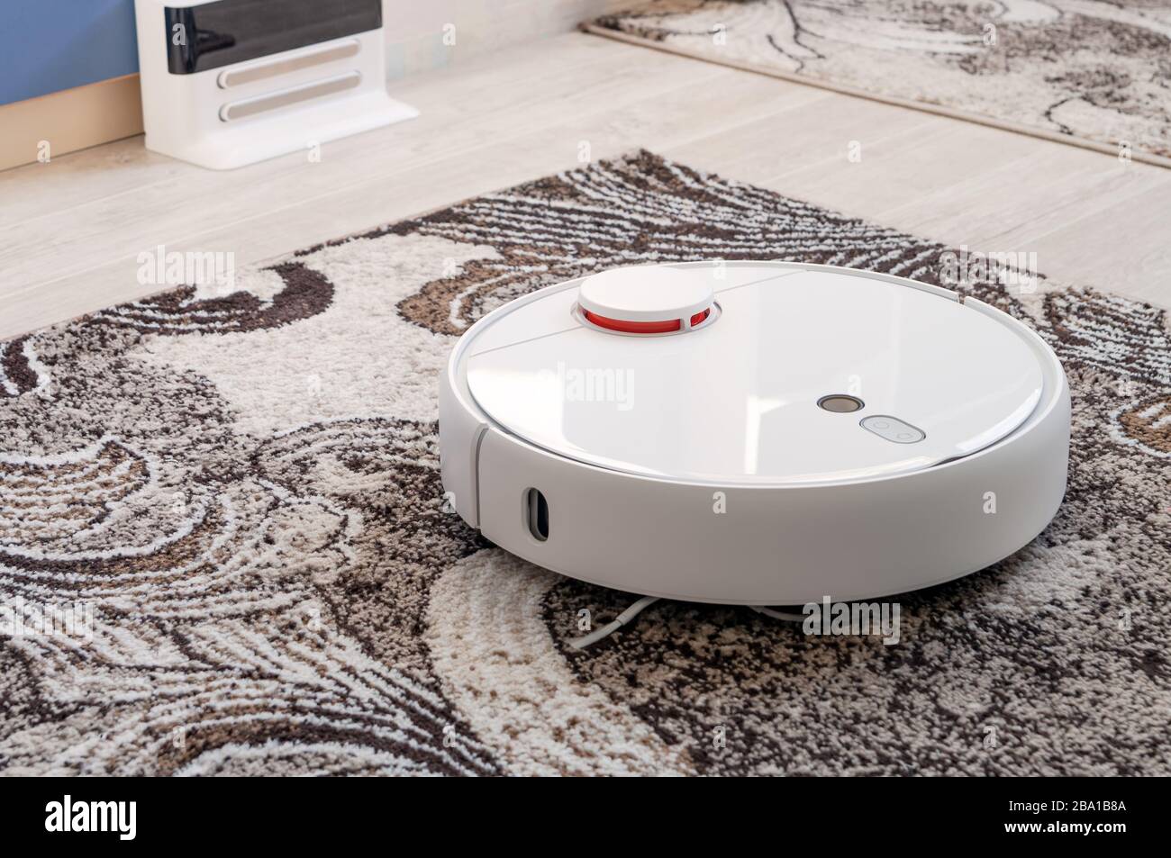 White round robotic vacuum cleaner on fitted carpet floor Stock Photo