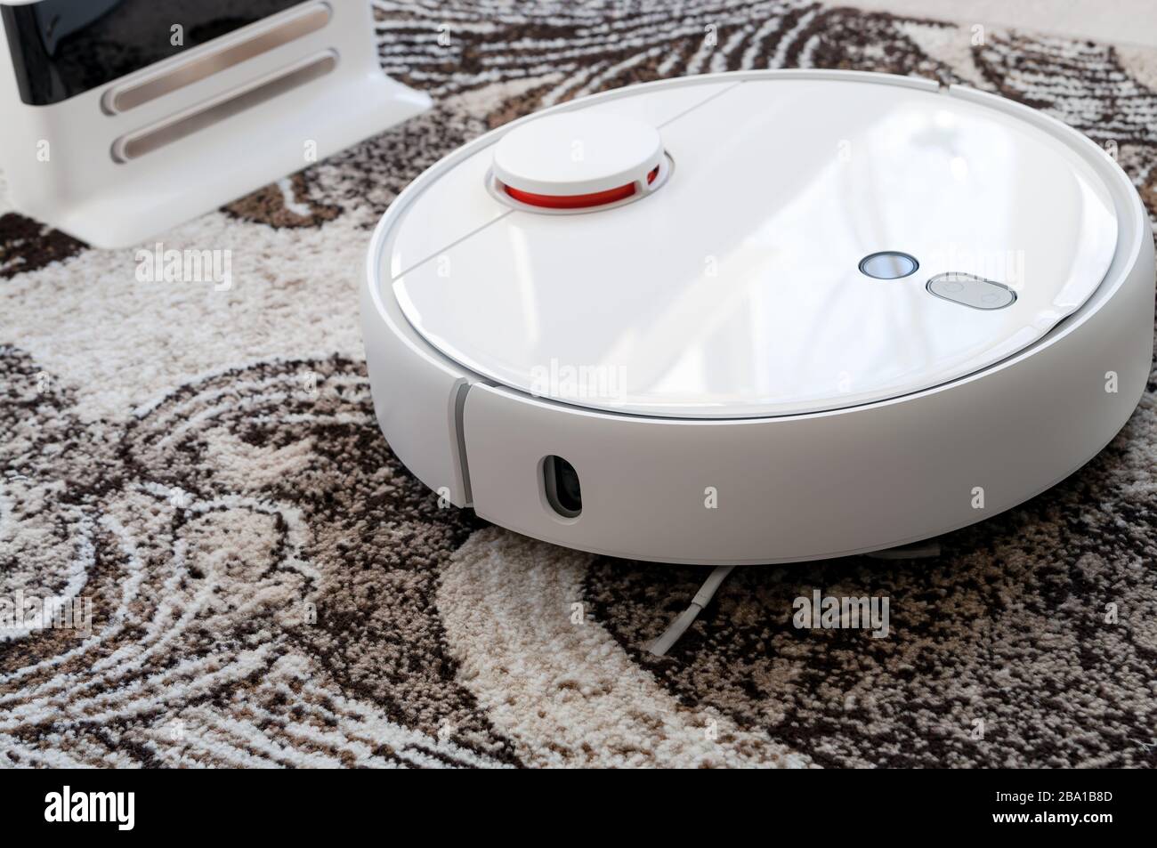 White round robotic vacuum cleaner on fitted carpet floor Stock Photo