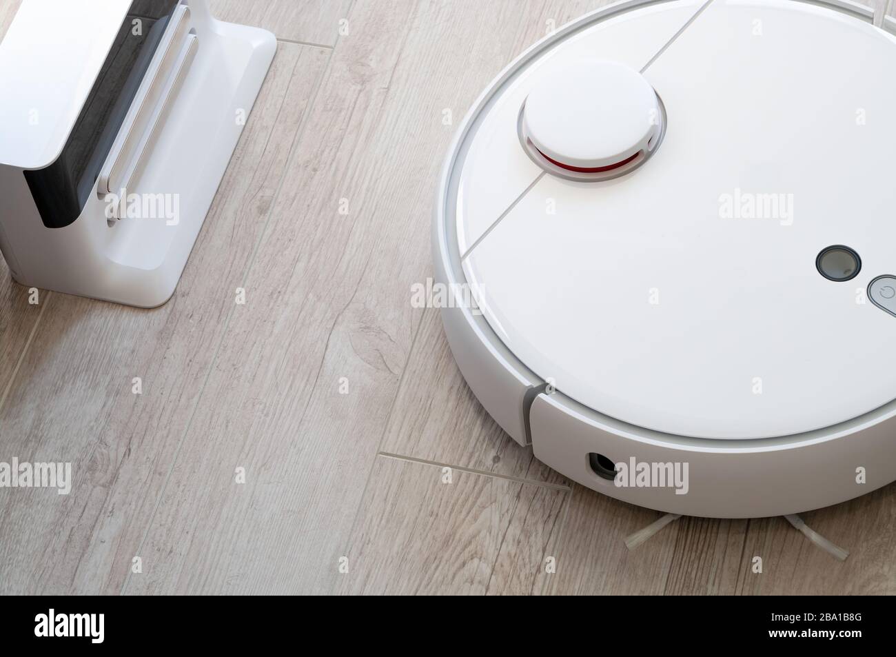 White round roboticobotic vacuum cleaner on laminate - technology housework Stock Photo