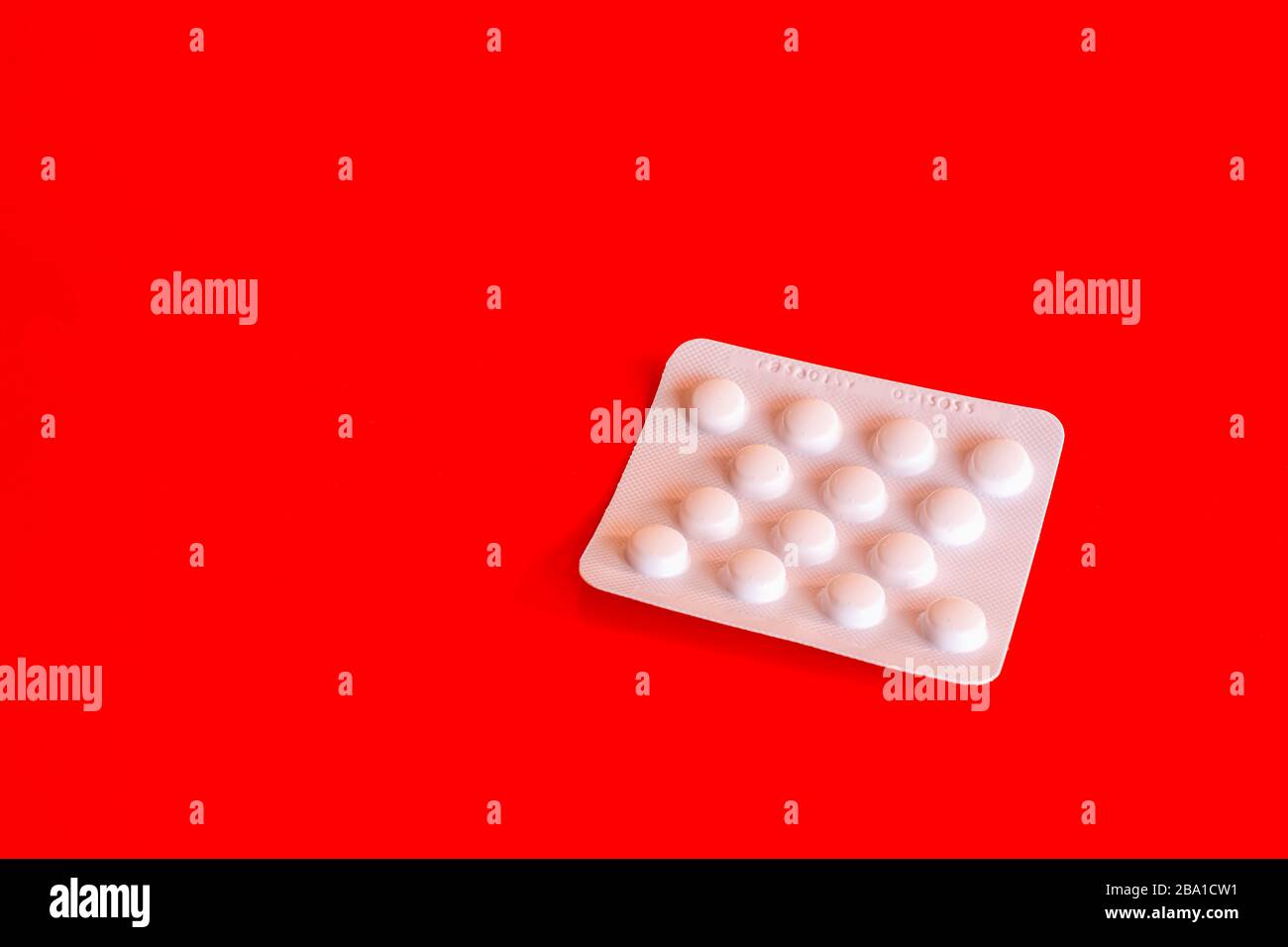 White blister of aspirin tablets on red background.Popular medication
