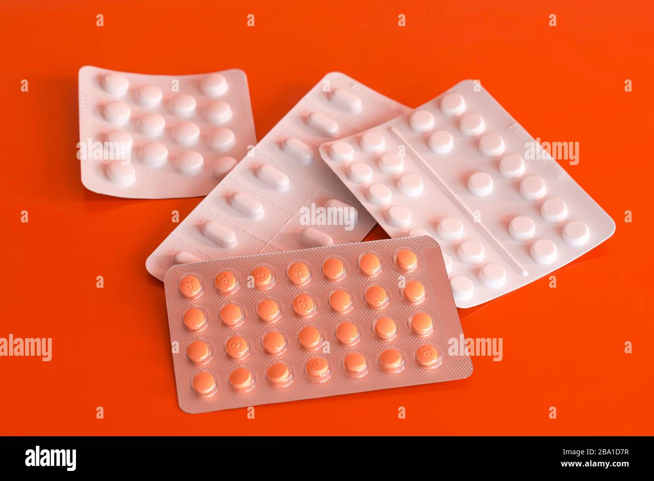 Four blisters of generic tablets on orange background.Various pills in plastic packages.Painkillers, hormones, antidepressants, aspirin.Popular meds. Stock Photo