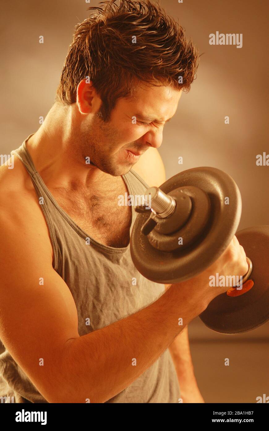 A strong man exercising with a dumb-bell Stock Photo