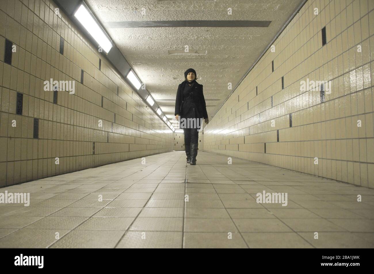 Young Adult Woman Walking through Underground Pedestrian Tunnel Stock Photo