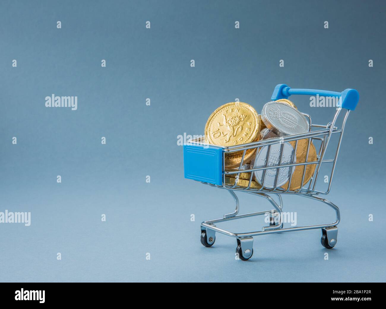 A concept of a Supermarket shopping trolley or cart full of cash, coins and money representing consumer spending at retail outlets with copy space Stock Photo