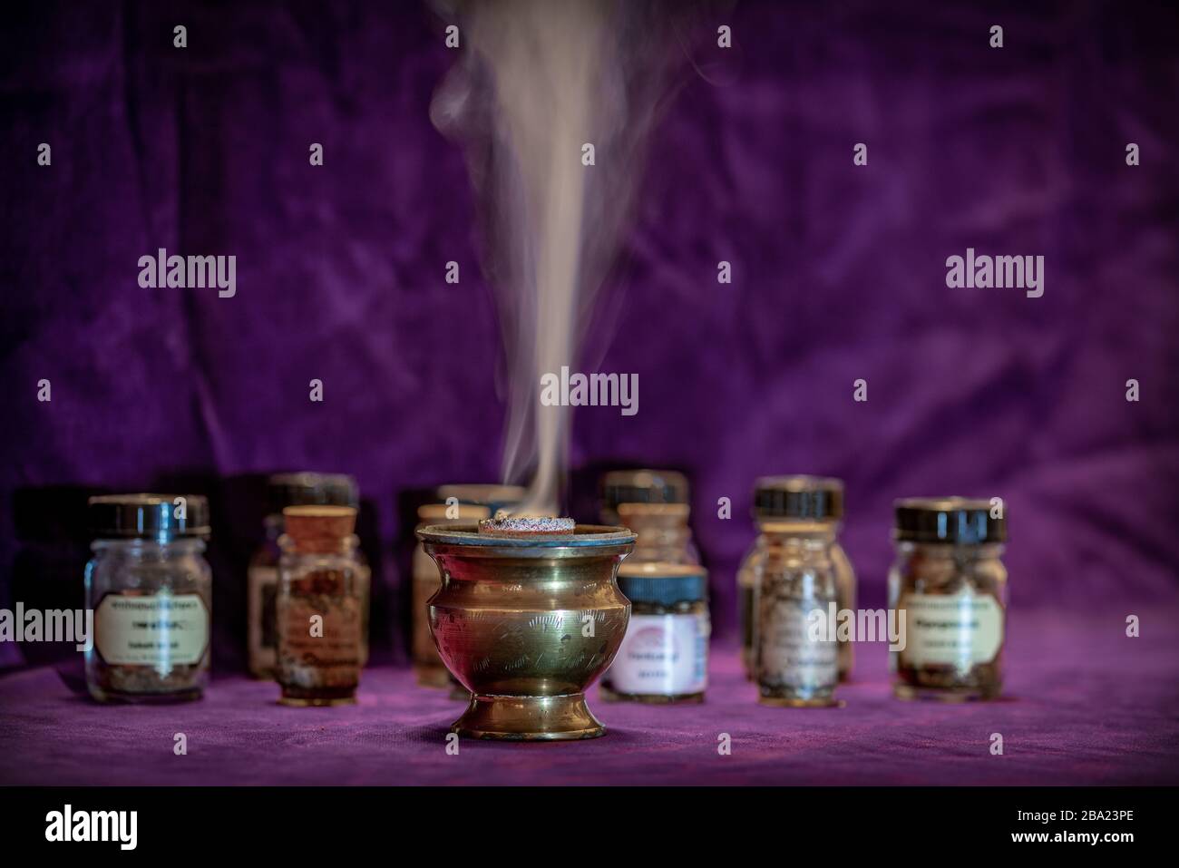 Smoke of burning white sage on an incense burner with more little