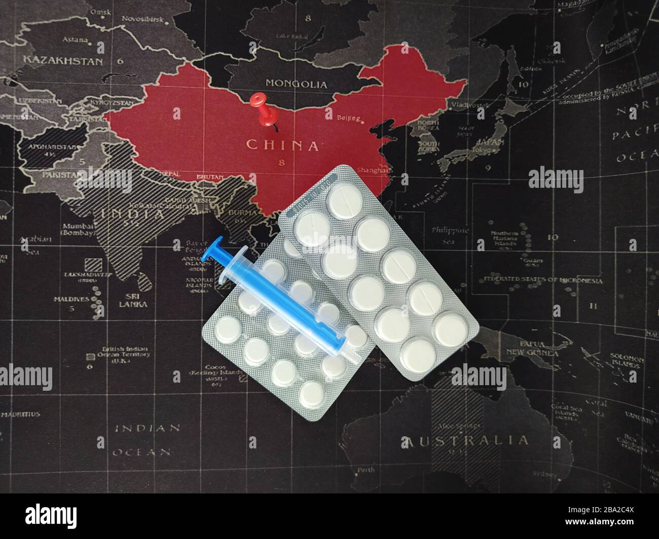 Coronavirus COVID-19. Cure concept representing the Chinese Wuhan's virus with pills and syringe. World map in the background. Dangerous flu strain ca Stock Photo