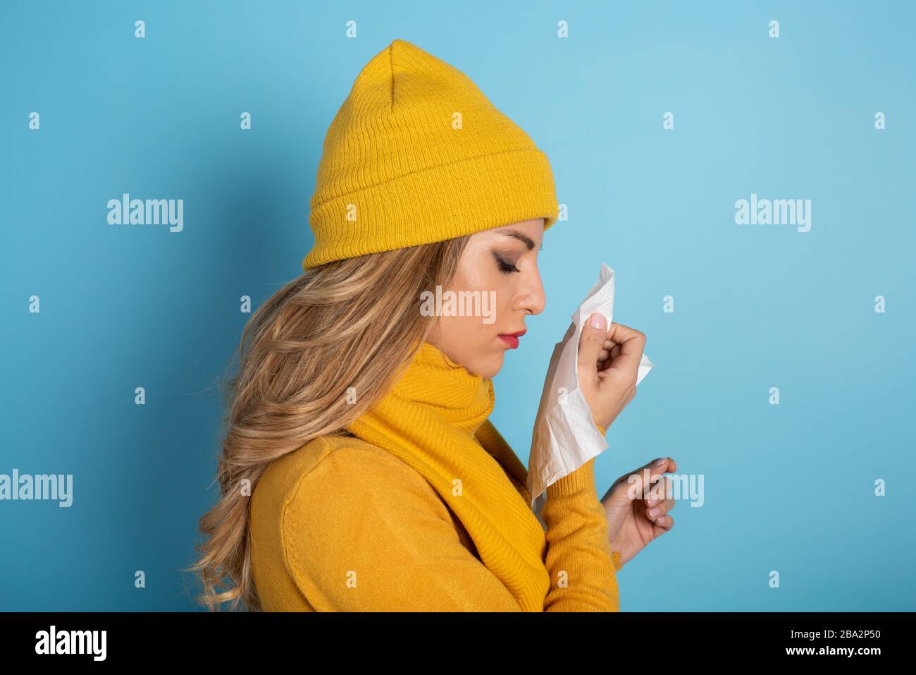 Girl caught a cold and wipes her nose. Cyan background Stock Photo