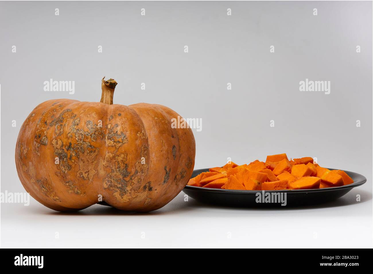 beautiful pumpkin and cut pumpkin on black plate on white background Stock Photo