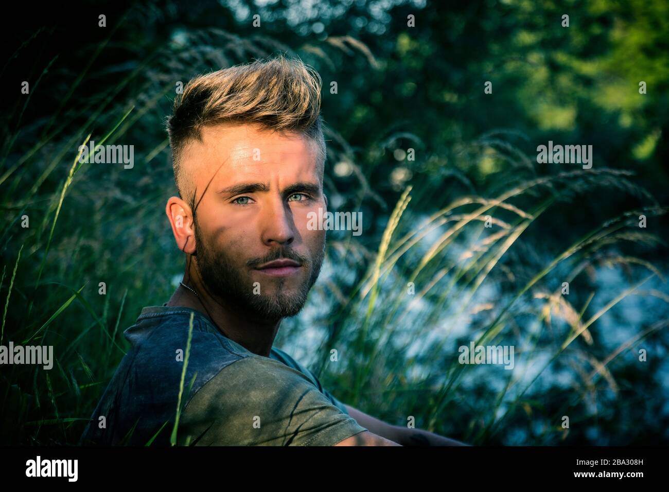 Blondish, blue eyed young man by river Stock Photo
